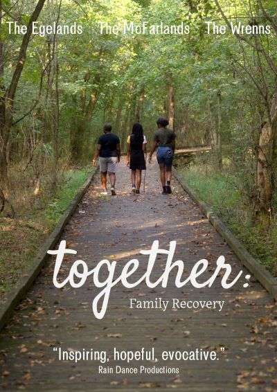 Three people walking on a trail through the woods, two adults and one teen. Image is for a movie starring The Egelands, The McFarlands, and The Wrens. It is called Together Family Recovery. 'Inspiring, hopeful, evocative.' Rain Dance Productions.